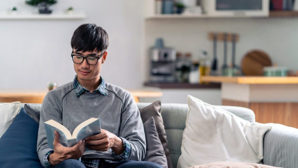 家で本を読んでいる男性